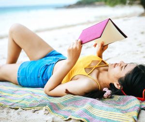 Teen girl reading on the beach